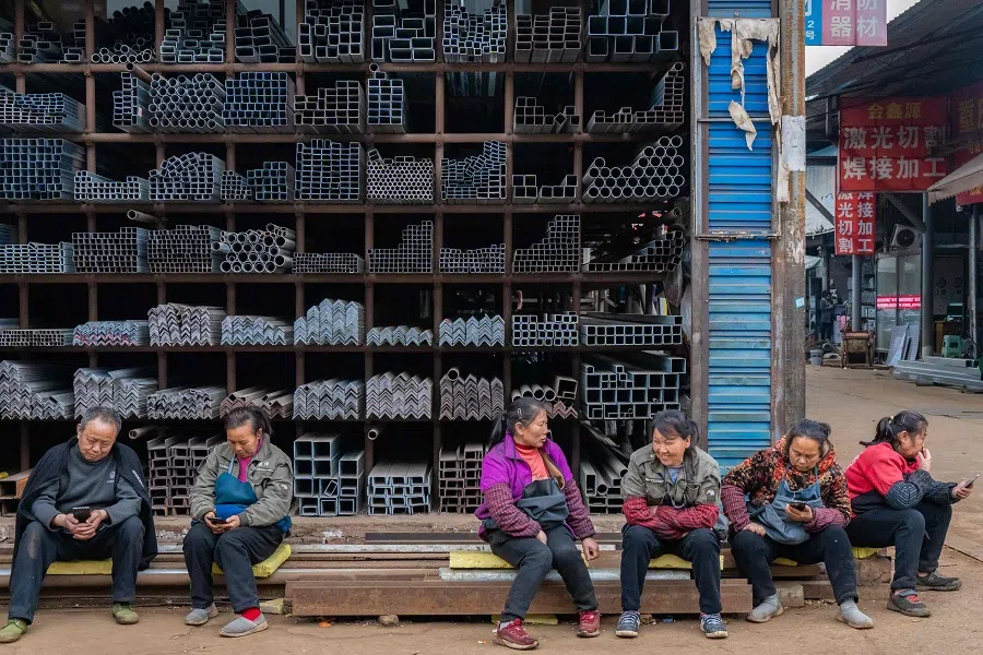 Workers sit in front of steel products at a steel market in southwestern China’s Chongqing municipality on 2 March 2025. (Stringer/AFP)