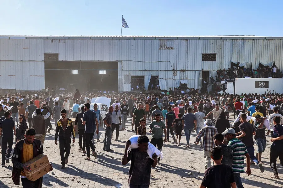 Displaced Palestinians ferry bags of food aid after storming a World Food Programme warehouse in Deir el-Balah in the central Gaza Strip on 28 May 2025. (Eyad Baba/AFP)