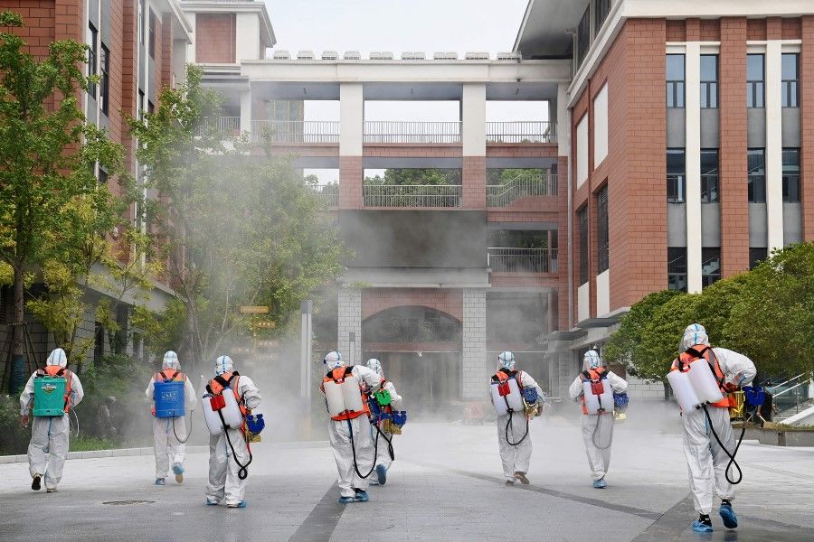 This photo taken on 25 August 2021 shows staff members spraying disinfectant at a primary school ahead of the new semester in Wuhan, in China's central Hubei province. (STR/AFP)