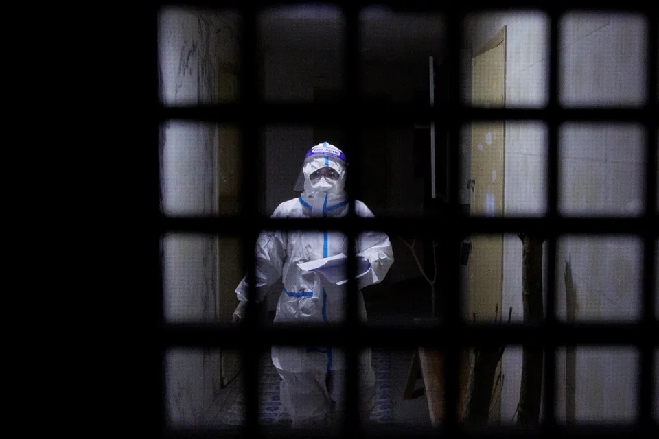 A pandemic prevention worker in a protective suit approaches an apartment in a building that went into lockdown as Covid-19 outbreaks continue in Beijing, China, 2 December 2022. (Thomas Peter/Reuters)