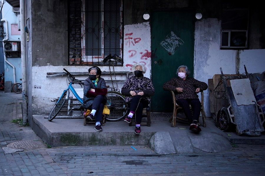 In this photo taken on 12 April 2020, residents wearing face masks are seen at a blocked residential area after the lockdown was lifted in Wuhan, China. (Aly Song/Reuters)