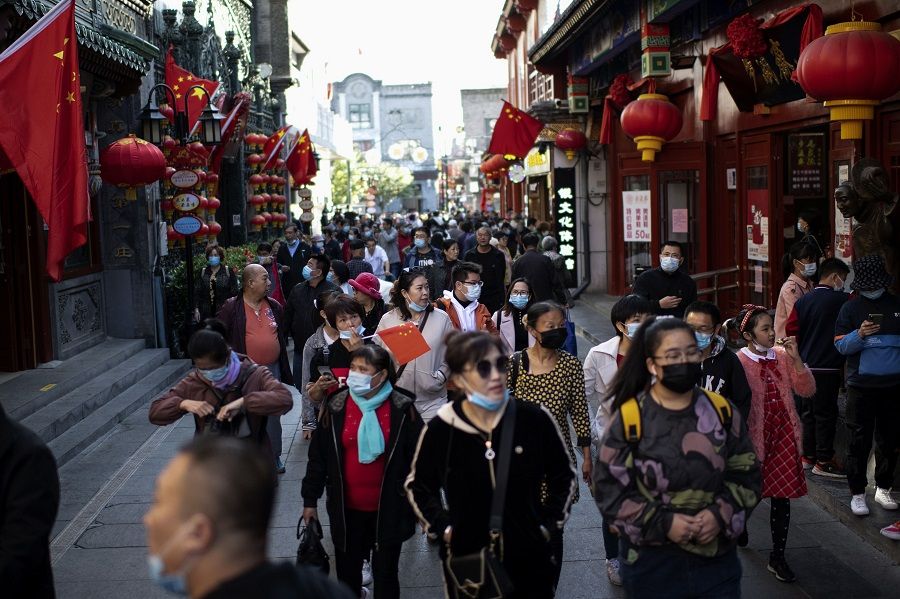People wearing face masks walk along Qianmen street to shop during the country's national "Golden Week" holiday in Beijing on 5 October 2020. (Noel Celis/AFP)