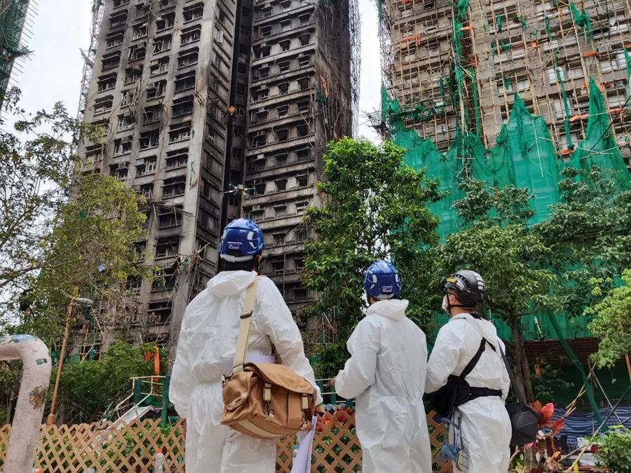 Members of the Hong Kong Police Forces’ Disaster Victims Identification Unit (DVIU) stand infront of a damaged building, following deadly fire at the Wang Fuk Court housing complex, in Hong Kong, China, on 30 November 2025.