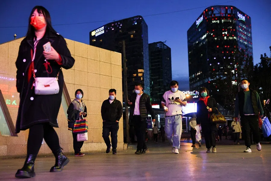 People enter a long distance bus station during evening rush hour in Beijing, China, 19 October 2021. (Thomas Peter/Reuters)