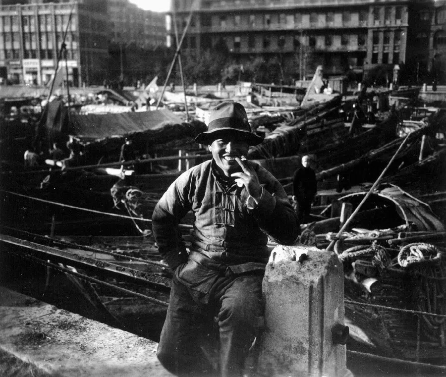 A boatman smiles as he smokes by the pier, the picture of contentment.