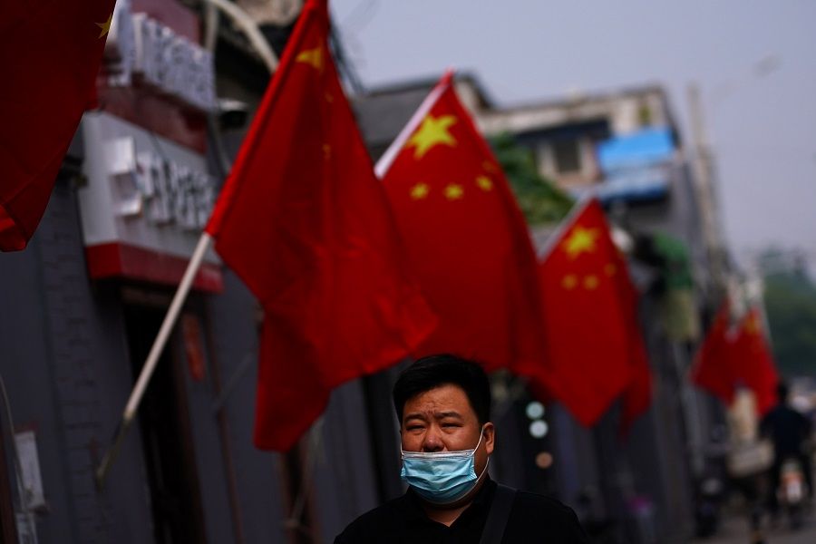 A man wearing a face mask following the Covid-19 outbreak walks past Chinese national flags set up ahead of China's National Day on 1 October in Beijing, China, 28 September 2020. (Tingshu Wang/Reuters)