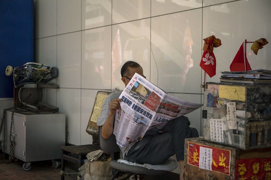 A stallholder reads a copy of the Ta Kung Pao newspaper showing a report on the passage of the new national security law in Hong Kong. The headline reads: "The Magic Ballast - National Security Law for Hong Kong Implemented." (Paul Yeung/Bloomberg)