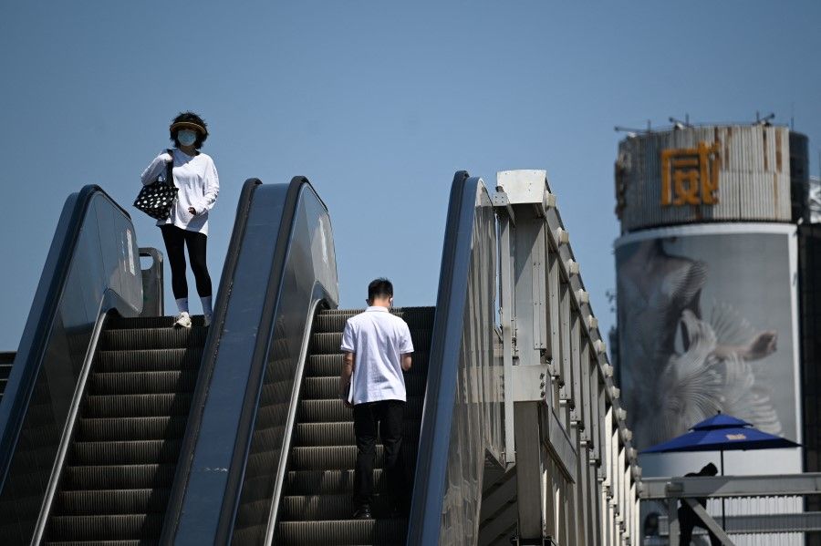People ride escalators at a business district in Beijing, China, on 16 May 2022. (Wang Zhao/AFP)