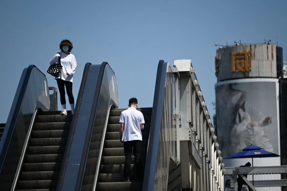 People ride escalators at a business district in Beijing, China, on 16 May 2022. (Wang Zhao/AFP)