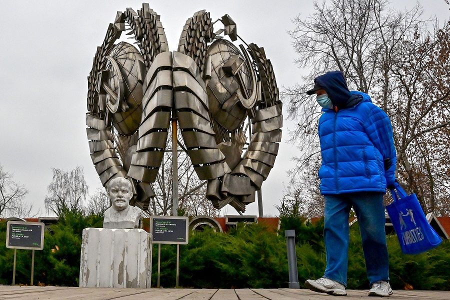 A pedestrian wearing a face mask, walks past a sculpture of the founder of the Soviet Union Vladimir Lenin and a State emblem of the USSR at a Modern History Sculpture Museum park in Moscow, Russia, on 3 November 2021. (Yuri Kadobnov/AFP)