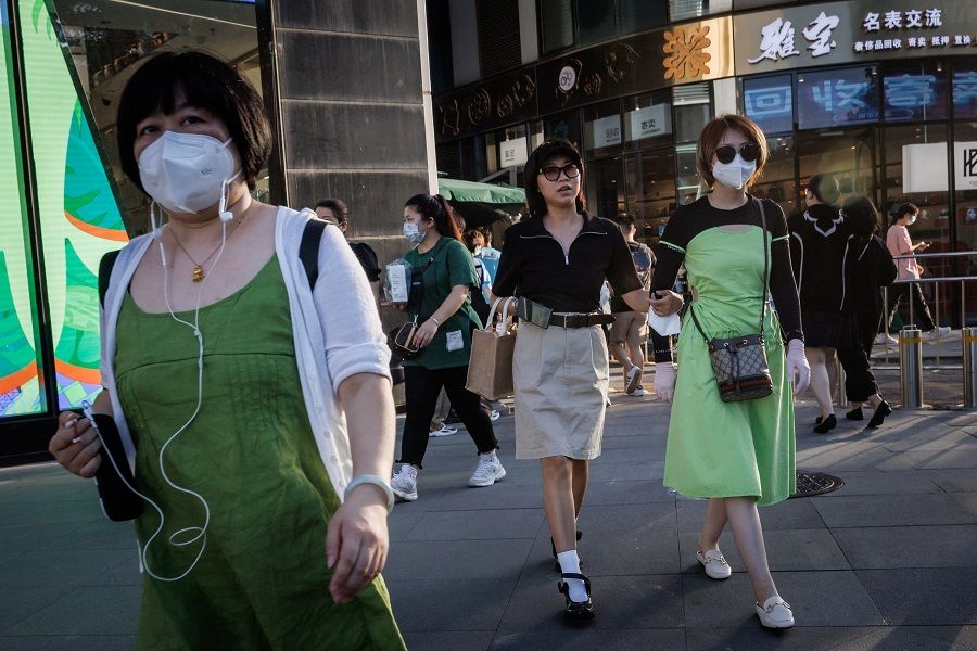 Shoppers walk in a retail district in Beijing, China, 13 July 2022. (Thomas Peter/Reuters)