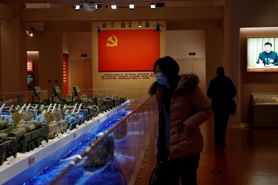 A visitor looks at models of Chinese military equipment in front of an exhibit of the Chinese Communist Party flag at an exhibition at the National Museum of China in Beijing, China, 3 March 2021. (Tingshu Wang/Reuters)