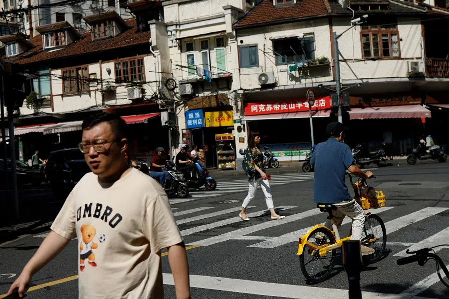People walk on a street in Shanghai, China, on 27 September 2024. (Tingshu Wang/Reuters)