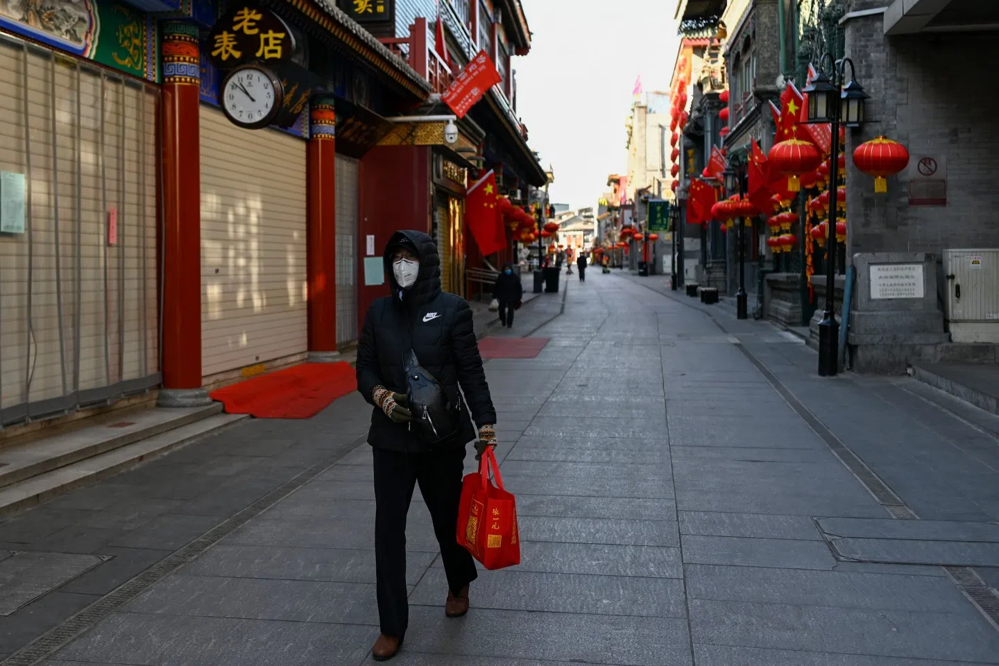 A woman walks along an empty business street in Beijing on 4 February 2020 during an especially quiet Chinese New Year. (Wang Zhao/AFP)