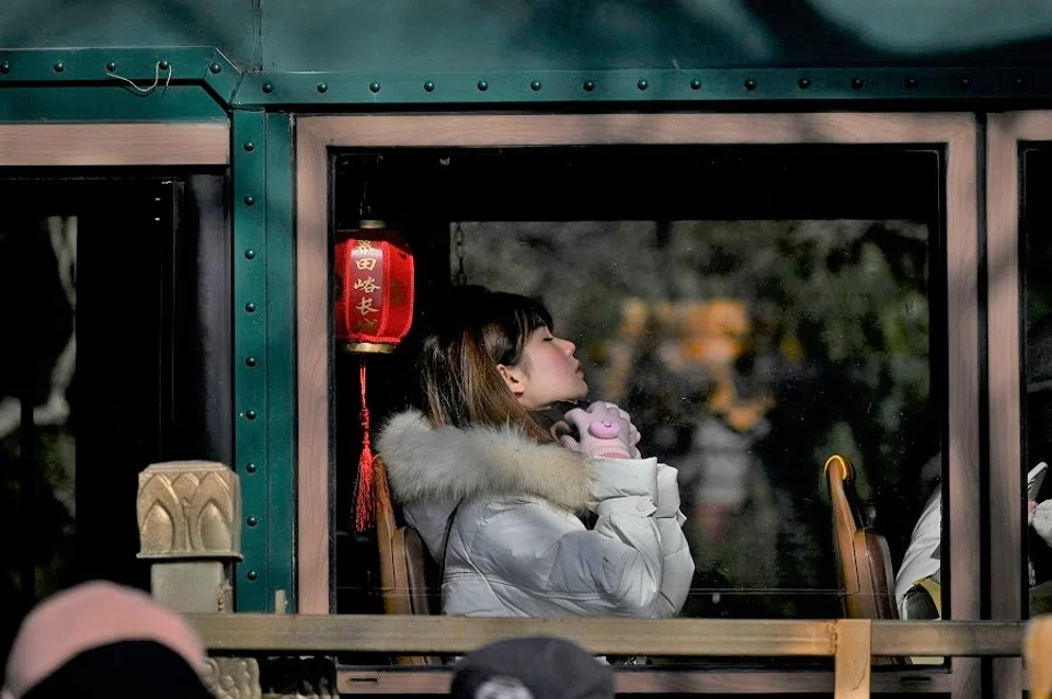 A woman rests on a tour bus outside the Forbidden City in Beijing, China, on 23 January 2023. (Wang Zhao/AFP)