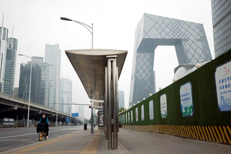 A man wearing a face mask cycles past the CCTV headquarters at the Central Business District in Beijing, China, 10 May 2022. (Carlos Garcia Rawlins/Reuters)