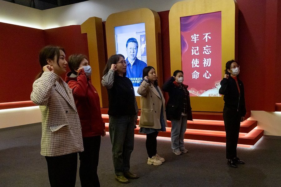 People swear an oath to the Chinese Communist Party in front of an installation that includes an image of Chinese President Xi Jinping at an exhibition marking the party's 100th founding anniversary in Beijing, China on 22 April 2021. (Thomas Peter/Reuters)
