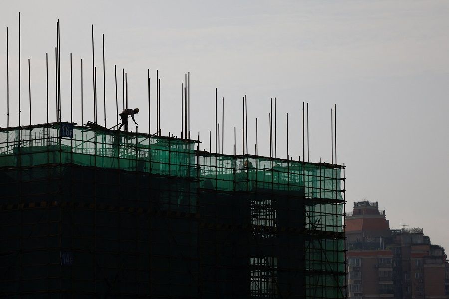 A worker assembles scaffoldings in a building under construction in Wuzhou, Guangxi Zhuang Autonomous Region, China, 25 March 2022. (Carlos Garcia Rawlins/Reuters)