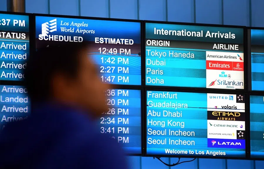 International flights arrivals are listed on a screen at Los Angeles International Airport on 12 March 2020. (Frederic J. Brown/AFP)