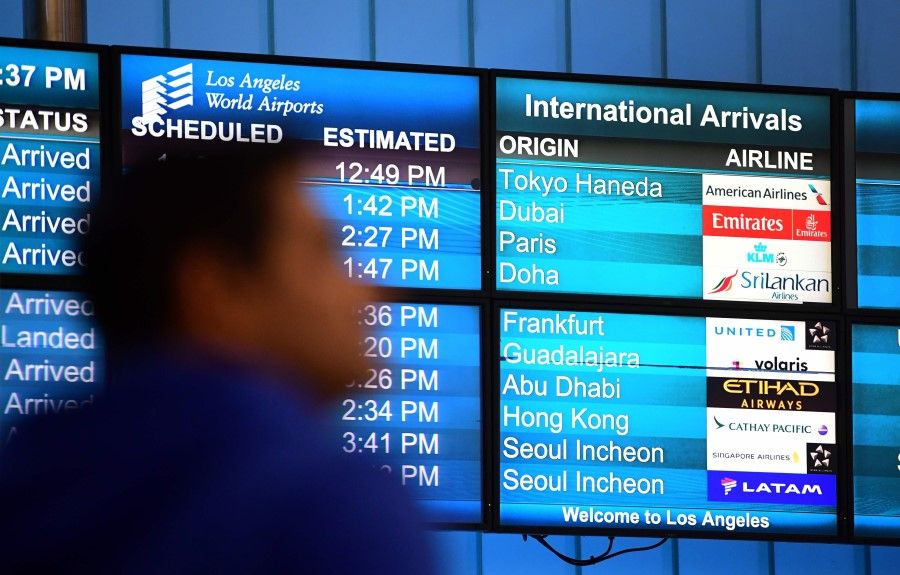 International flights arrivals are listed on a screen at Los Angeles International Airport on 12 March 2020. (Frederic J. Brown/AFP)
