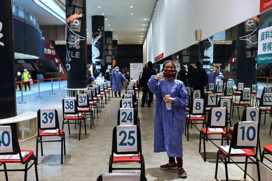 A staff gives orders while people receive booster shots of the Covid-19 vaccine at a square in Taipei, Taiwan, 17 January 2022. (Ann Wang/Reuters)