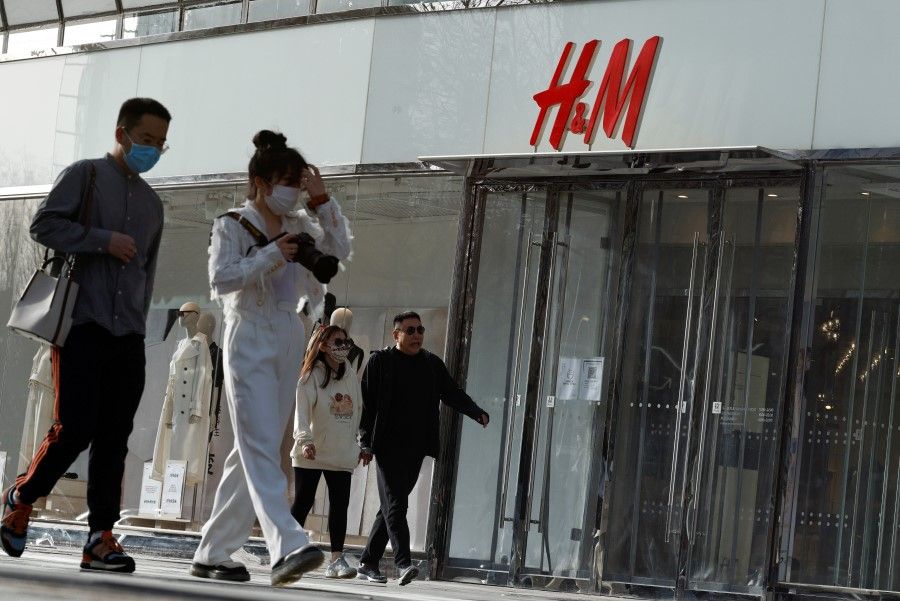 People walk past an H&M store in a shopping area in Beijing, China, 28 March 2021. (Thomas Peter/Reuters)