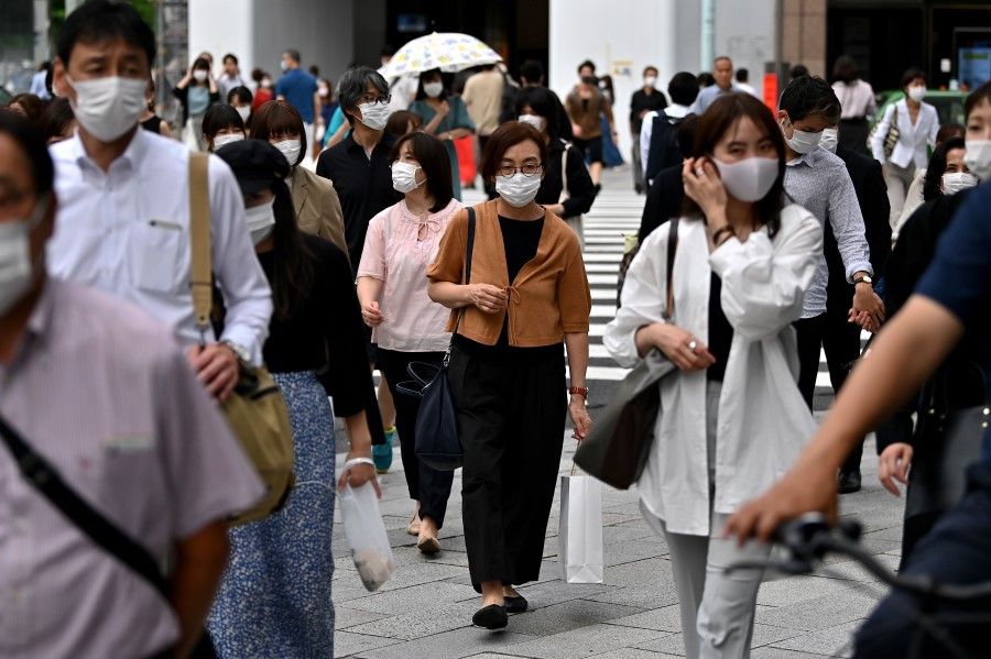 Pedestrians wearing face masks cross the street in the Ginza area in Tokyo, 23 June 2020. (Charly Triballeau/AFP)