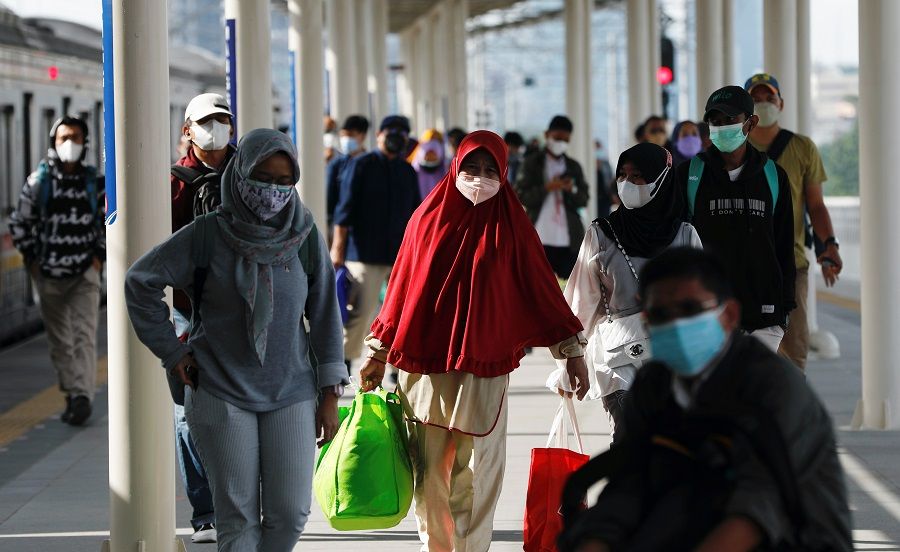People wearing protective face masks walk at a train station in Jakarta, Indonesia, 22 November 2021. (Ajeng Dinar Ulfiana/Reuters)