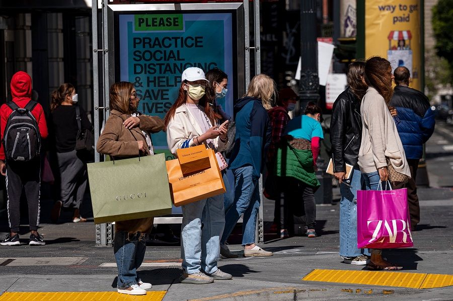 People wearing protective masks carry shopping bags while waiting to cross Geary Street in San Francisco, California on 10 June 2021. (David Paul Morris/Bloomberg)
