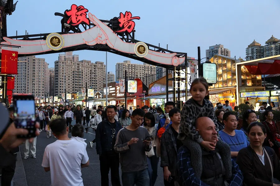 People walk on a street with food shops during the five-day Labour Day holiday in Shanghai, China, on 4 May 2025. (Go Nakamura/Reuters)