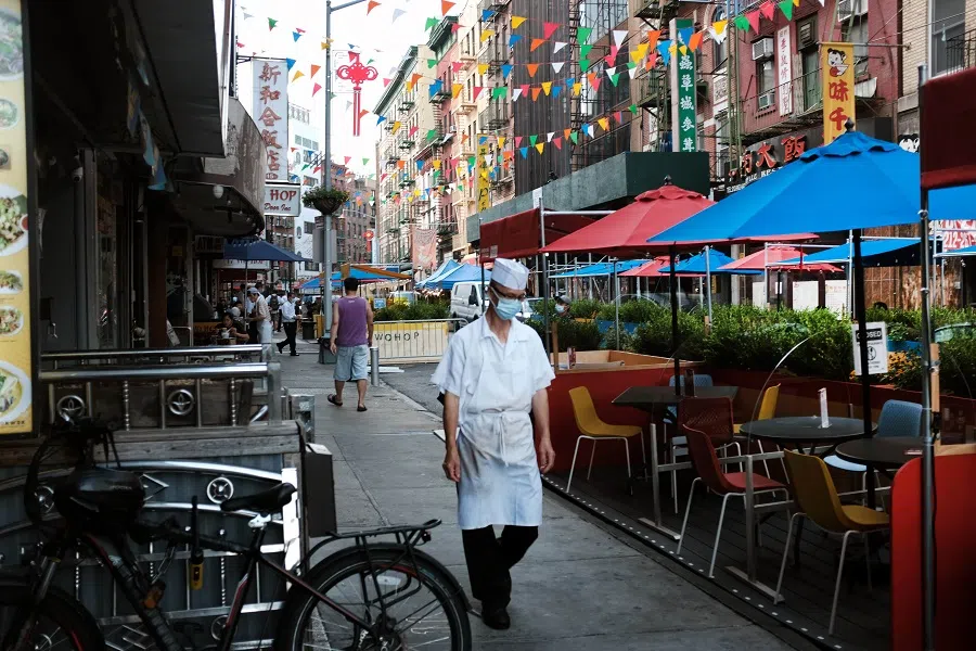 A worker walks past an outdoor dining area in New York City's Chinatown on 10 August 2020 in New York City. (Spencer Platt/Getty Images/AFP)
