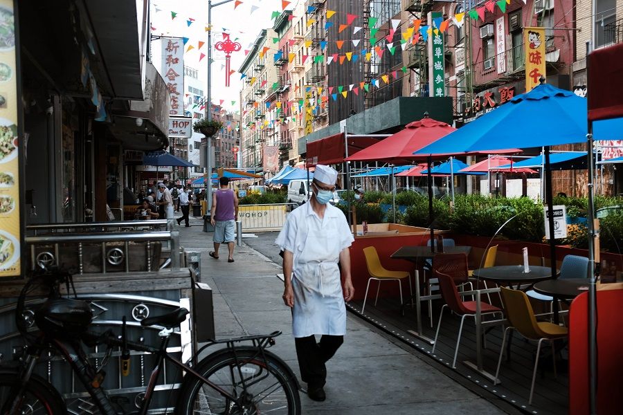 A worker walks past an outdoor dining area in New York City's Chinatown on 10 August 2020 in New York City. (Spencer Platt/Getty Images/AFP)