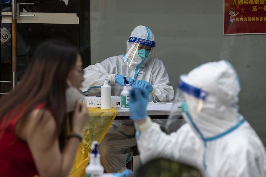 Healthcare workers in protective gear give residents their Covid-19 tests in Shanghai, China, on 10 July 2022. (Qilai Shen/Bloomberg)