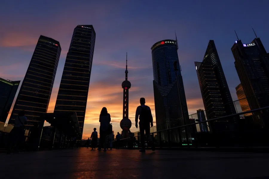 People walk in Lujiazui financial district during sunset in Pudong, Shanghai, China, 13 July 2021. (Aly Song/Reuters)
