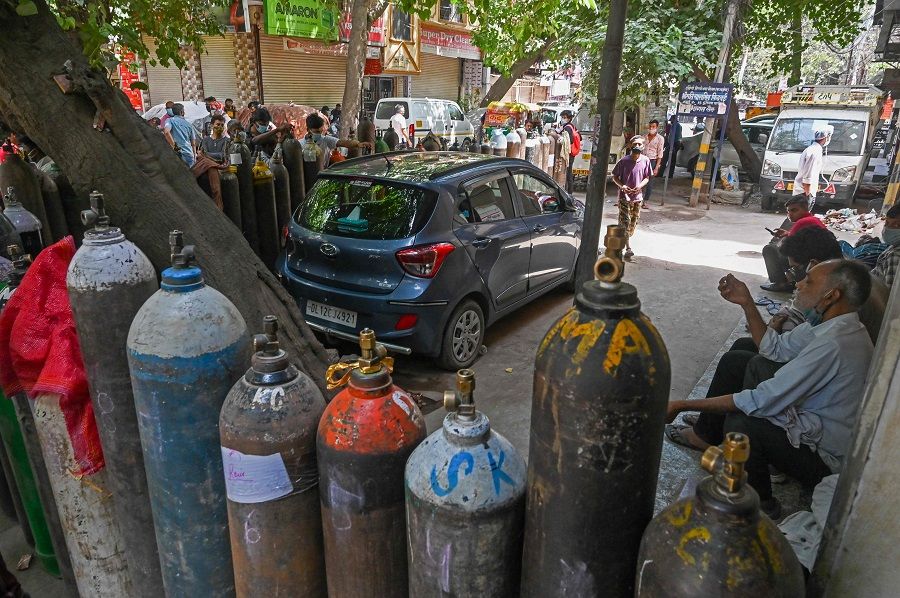People wait to refill their medical oxygen cylinders for Covid-19 coronavirus patients under home quarantine at a private refill centre in New Delhi, India on 4 May 2021. (Prakash Singh/AFP)