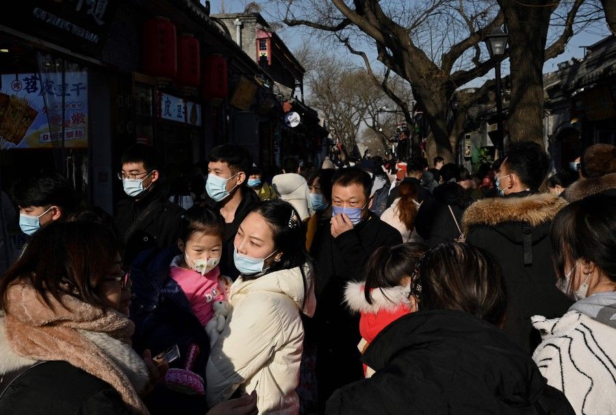 People walk through Nanluoguxiang alley in Beijing on New Year's Day on 1 January 2022. (Noel Celis/AFP)
