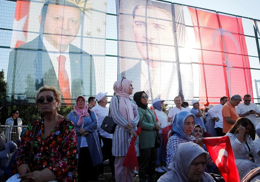 People stand next to flags with images of Turkish President Tayyip Erdoğan and modern Turkey’s founder Ataturk as they take part in an event marking the seventh anniversary of the attempted coup, at Beylerbeyi Stadium in Istanbul, Turkey, on 15 July 2023. (Dilara Senkaya/Reuters)