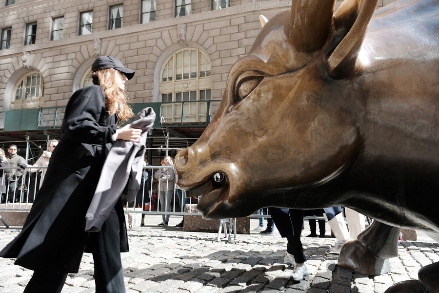 People walk by the Wall Street Bull in the Financial District on 7 March 2023 in New York City, US. (Spencer Platt/Getty Images/AFP)