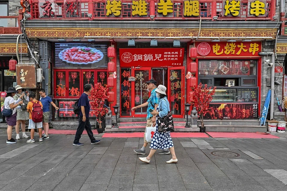 People walk along the Huguosi Street, Xicheng district, a dedicated food street in Beijing, China, on 23 August 2024. (Adek Berry/AFP)