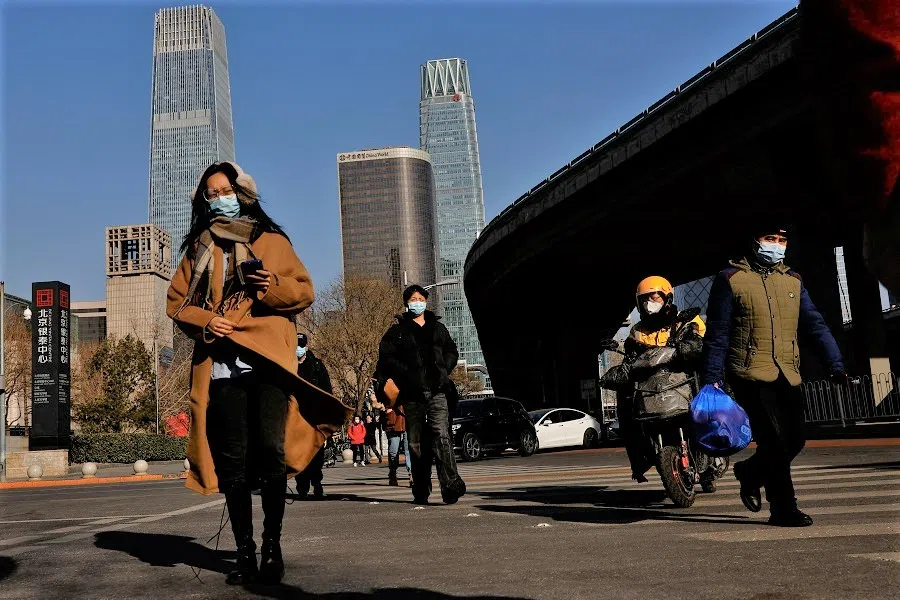 People walk on a street in the Beijing's central business district (CBD), during the morning rush hour, in Beijing, China, 30 January 2023. (Tingshu Wang/Reuters)