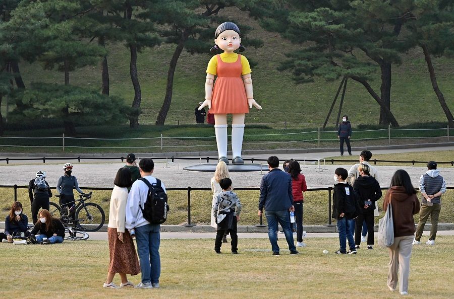 Visitors gather in front of a model of the doll named 'Younghee' - featured in the Netflix series Squid Game - displayed at a park in Seoul, South Korea, on 26 October 2021. (Jung Yeon-je/AFP)
