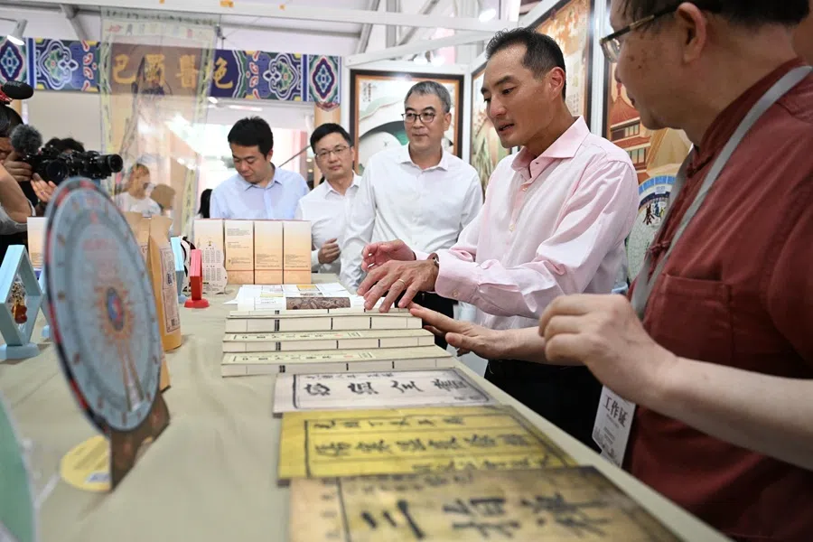Senior Minister of State for Digital Development and Information Tan Kiat How (second from right) at a traditional Chinese medicine booth at the 2025 Chongqing Week on 11 June 2025. (SPH Media)