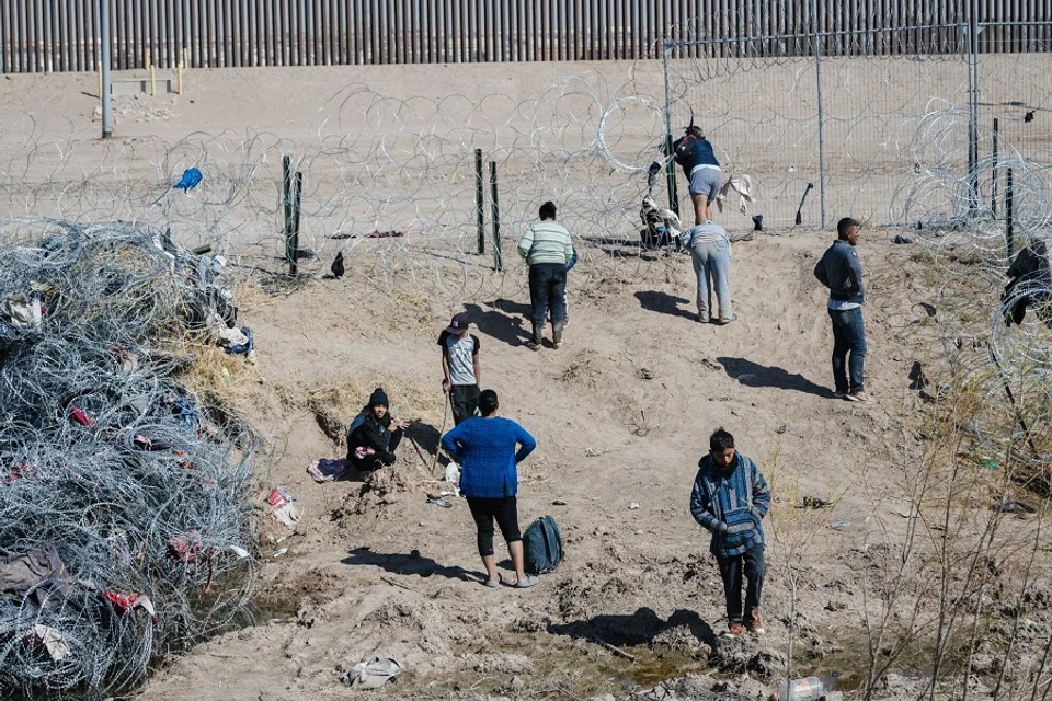 Migrants look for a way past concertina wire after crossing the US-Mexico border through the Rio Grande River into El Paso, Texas, seen from Ciudad Juarez, Chihuahua state, Mexico, on 8 February 2024. (Justin Hamel/Bloomberg)
