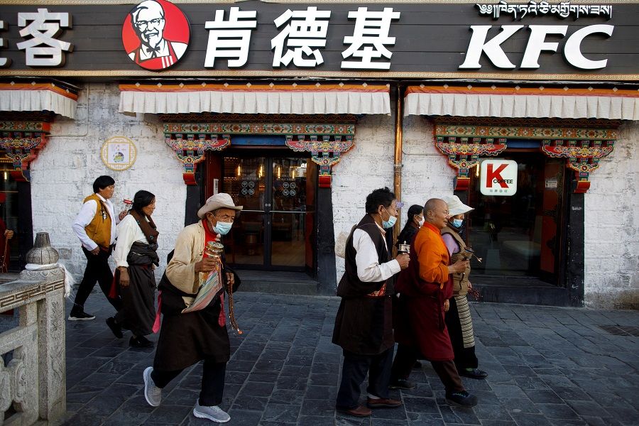 Tibetans walk past a KFC fast food restaurant as they perform a pilgrimage around the Jokhang Temple in Lhasa, during a government-organised tour of the Tibet Autonomous Region to showcase poverty alleviation in China, 15 October 2020. (Thomas Peter/Reuters)