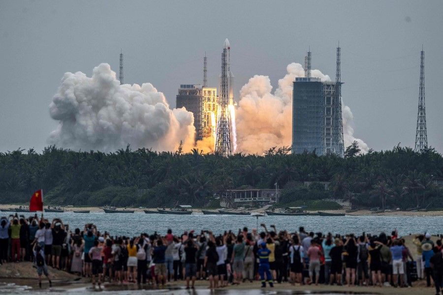 People watch a Long March 5B rocket, carrying China's Tianhe space station core module, as it lifts off from the Wenchang Space Launch Center in southern China's Hainan province on 29 April 2021. (STR/AFP)