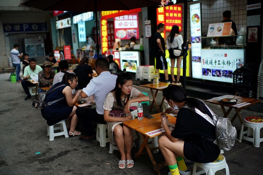 People eat at food stalls on a street in Chengdu, Sichuan, China, 8 September 2020. (Tingshu Wang/Reuters)