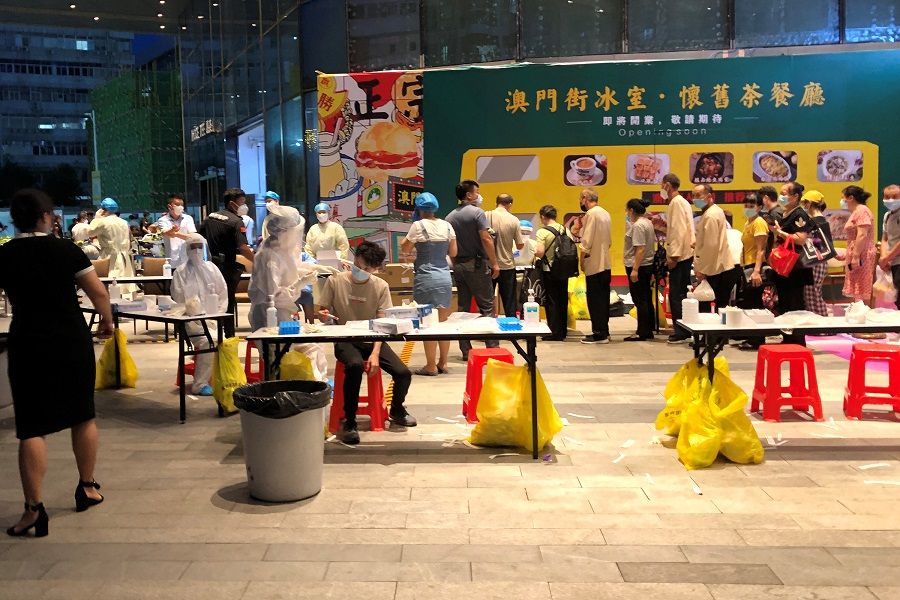 Medical workers wearing protective suits are seen at a nucleic acid testing site outside the IBC Mall in Shenzhen, Guangdong, China, 14 August 2020. (David Kirton/Reuters)