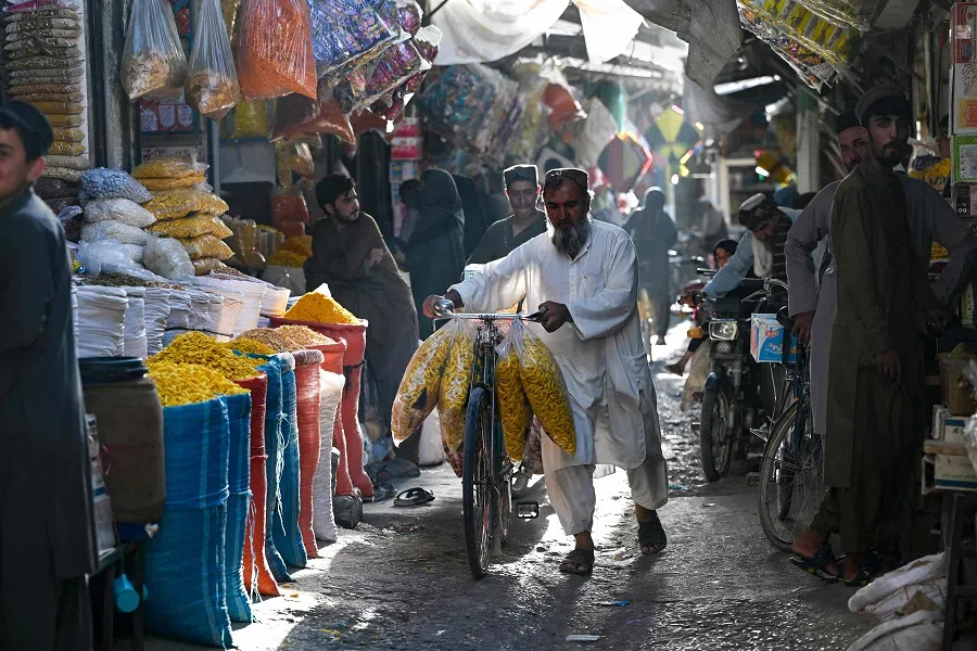An Afghan man with his bicycle walks through a market in Kandahar on 24 August 2024. (Wakil Kohsar/AFP)