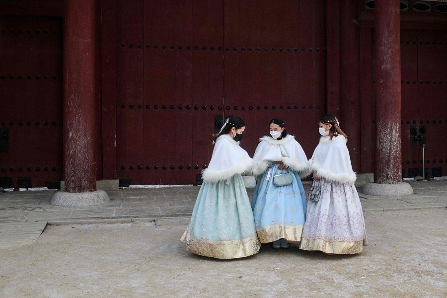 Visitors wear traditional hanbok dresses on the grounds of the Gyeongbokgung Palace after snowfall in Seoul, South Korea, on 17 January 2022. (Anthony Wallace/AFP)
