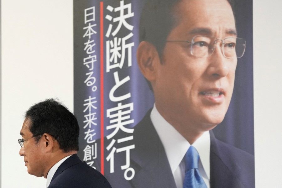 Fumio Kishida, Japan's Prime Minister and president of the Liberal Democratic Party (LDP), walks past his poster after placing a paper rose on an LDP candidate's name, to indicate a victory in the upper house election, at the party's headquarters in Tokyo, Japan, 10 July 2022. (Toru Hanai/Pool via Reuters)